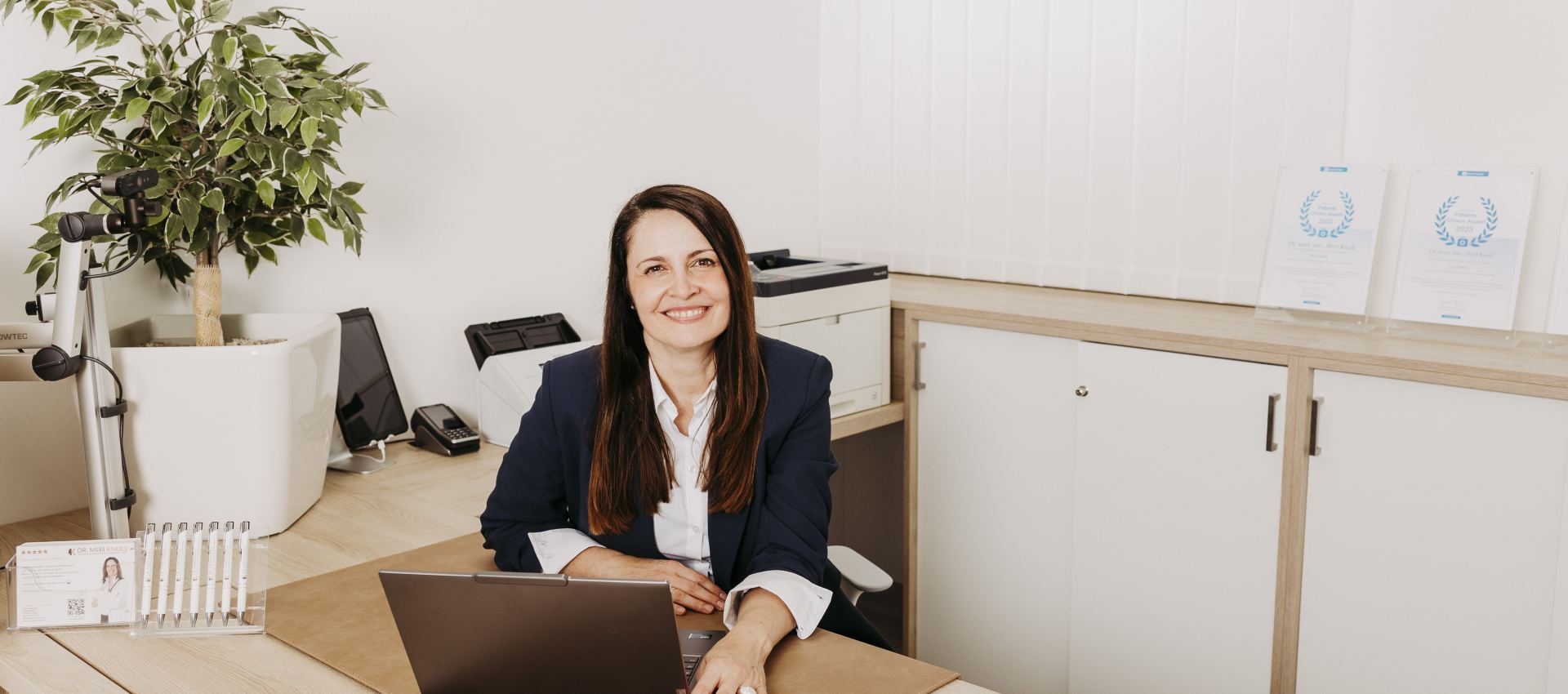 Dr. Meri Knoll sitz am Bürotisch vor dem Laptop. 